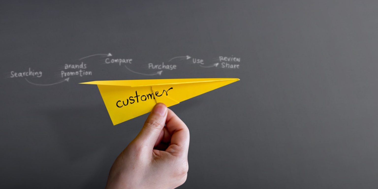 customer-journey-experience-concept-hand-raise-up-paper-plane-against-wall-Large